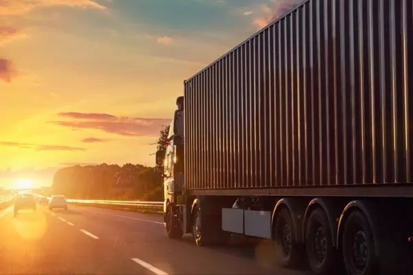 A large truck driving on a highway at sunset, representing cargo to Malaysia services