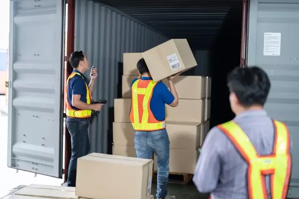 Team of workers handling packages in a warehouse, representing delivery to Malaysia